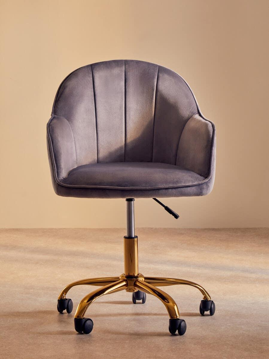 Grey velvet office chair with gold base and wheels on beige floor