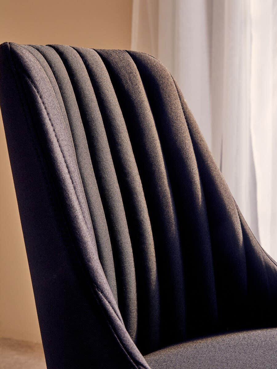 Close view of dark fabric dining chair with vertical stitched detail on backrest