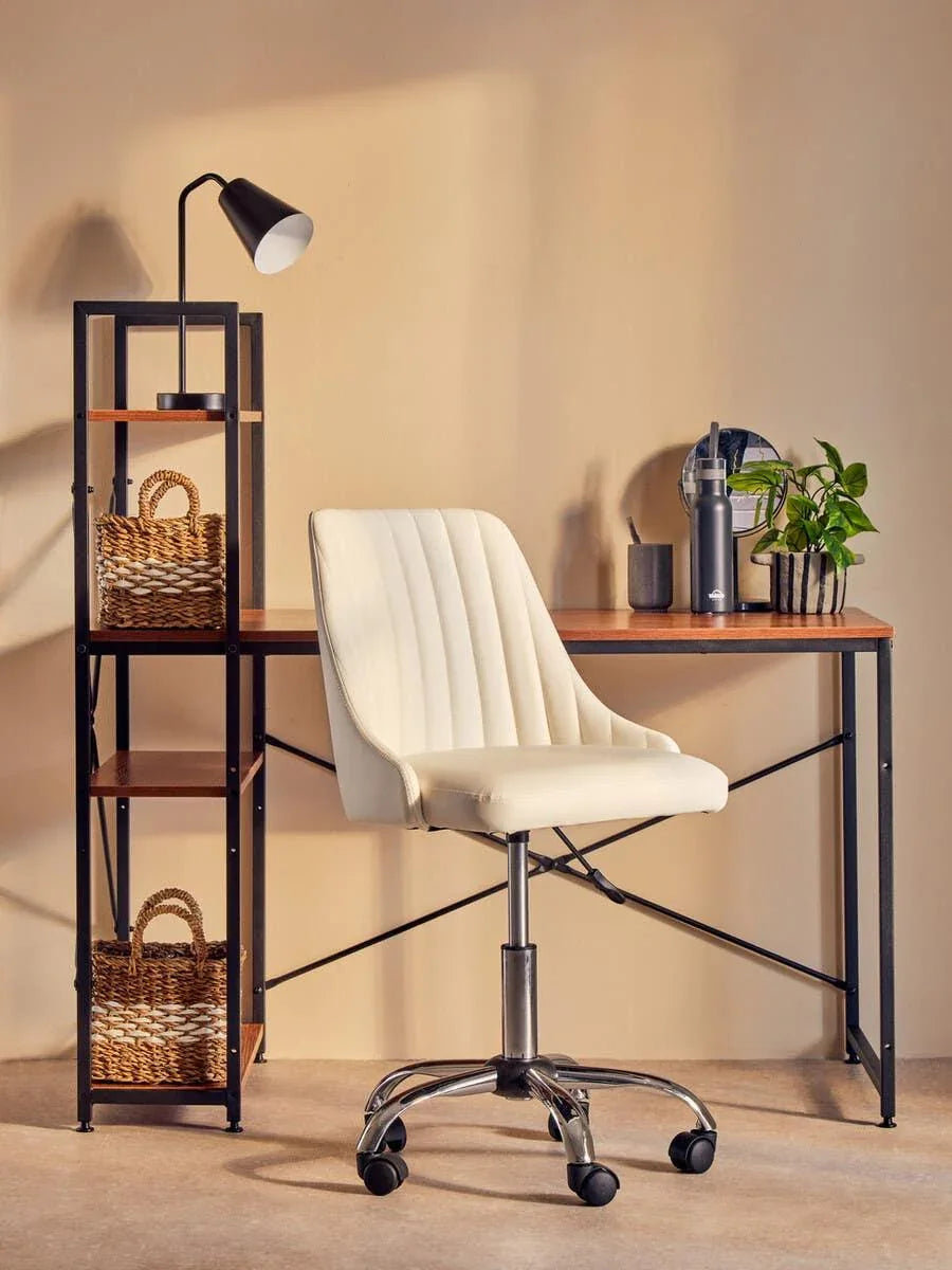 Cream office chair with chrome base at wooden desk with shelving and black desk lamp