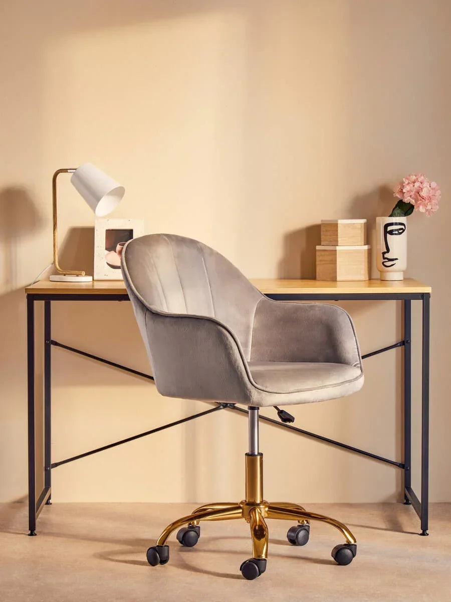 Grey velvet office chair with gold base at minimalist desk with lamp and vase