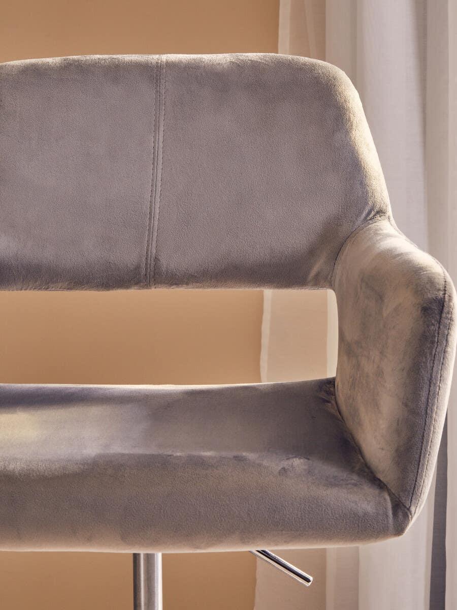 Grey velvet bar stool with chrome base and adjustable lever, close-up of backrest