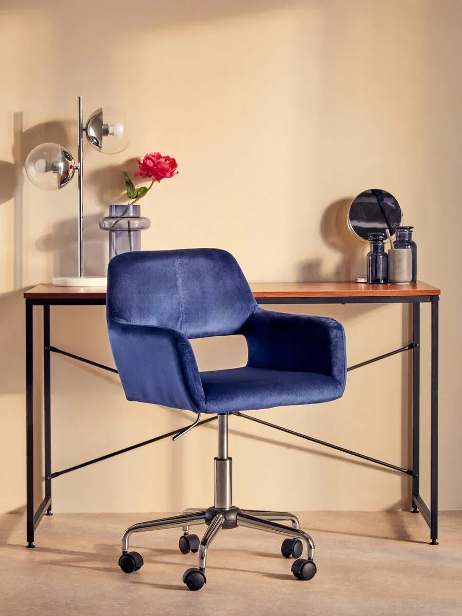 Blue velvet office chair with metal base on castors at modern wood desk