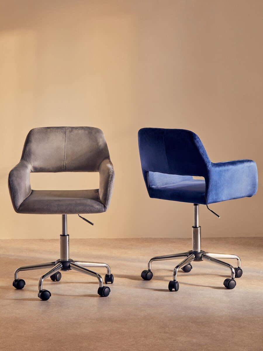 Grey and blue velvet office chairs with metal bases and casters on neutral background