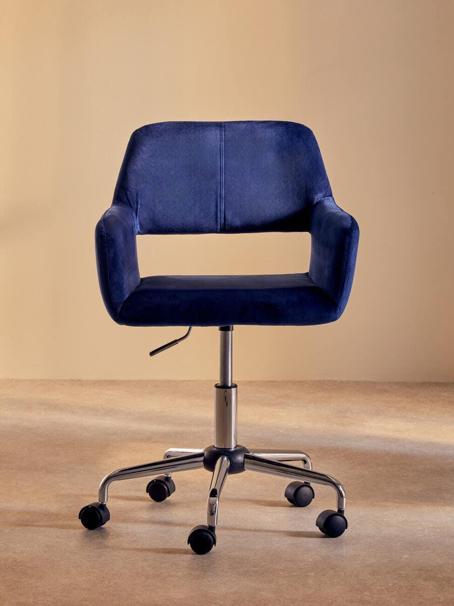 Blue velvet office chair with chrome base and castor wheels on beige background
