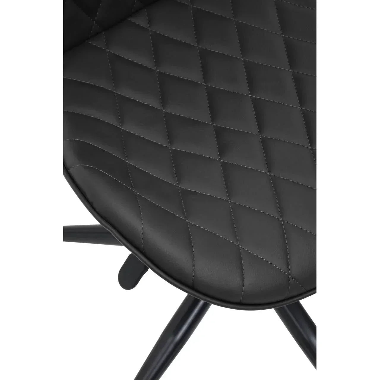 Closeup of black faux leather dining chair seat with diamond stitch pattern and metal legs