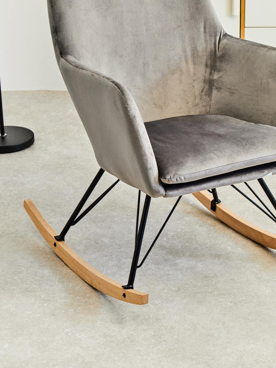 Velvet upholstered rocking chair with black metal legs and wooden rockers on grey floor
