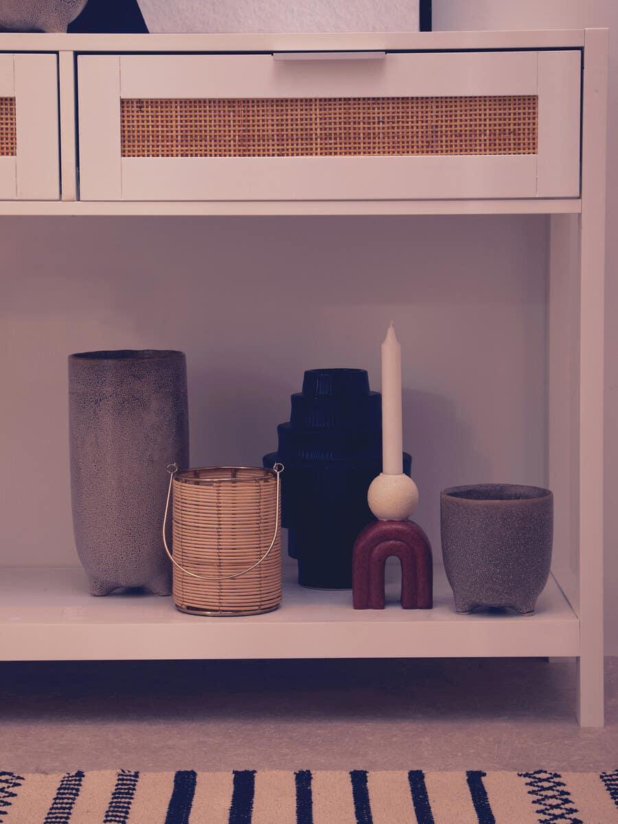 White console table with rattan drawer panel and assorted decorative vases and candle holder