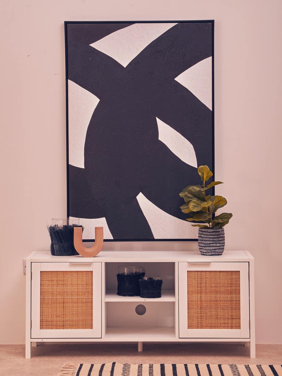 White sideboard with rattan doors, abstract wall art, decorative plant and accessories