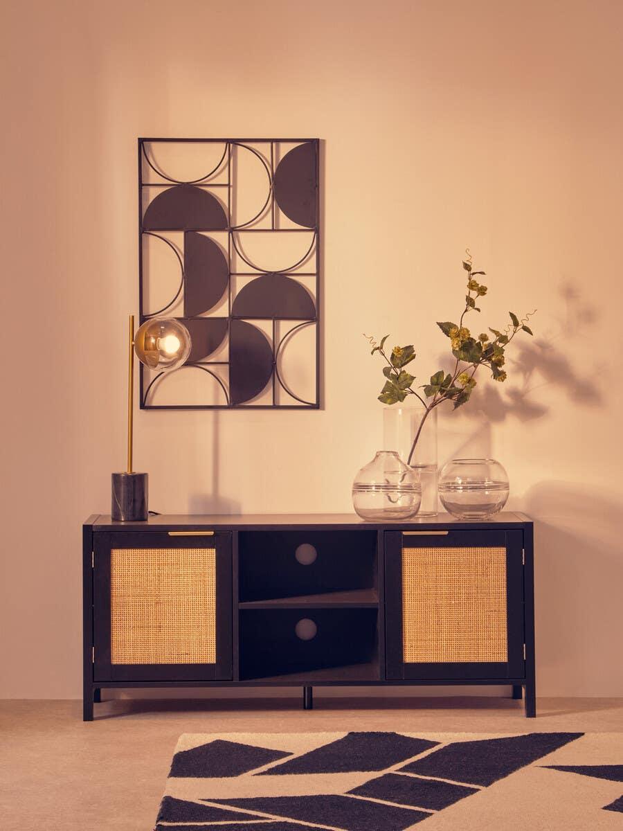 Black and rattan sideboard cabinet with open shelves, glass vases, and brass table lamp