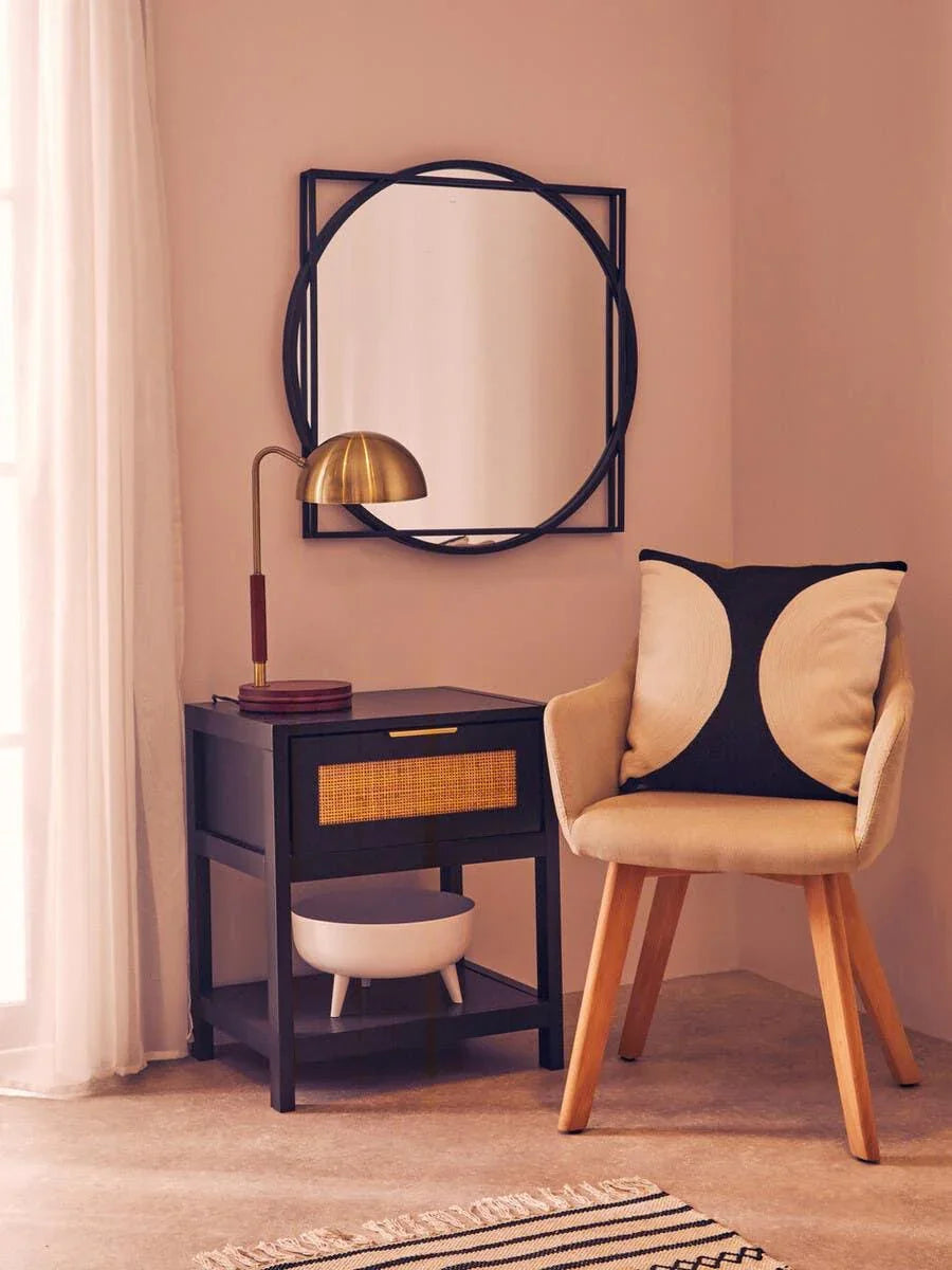 Contemporary side table with rattan drawer beside accent chair and round wall mirror