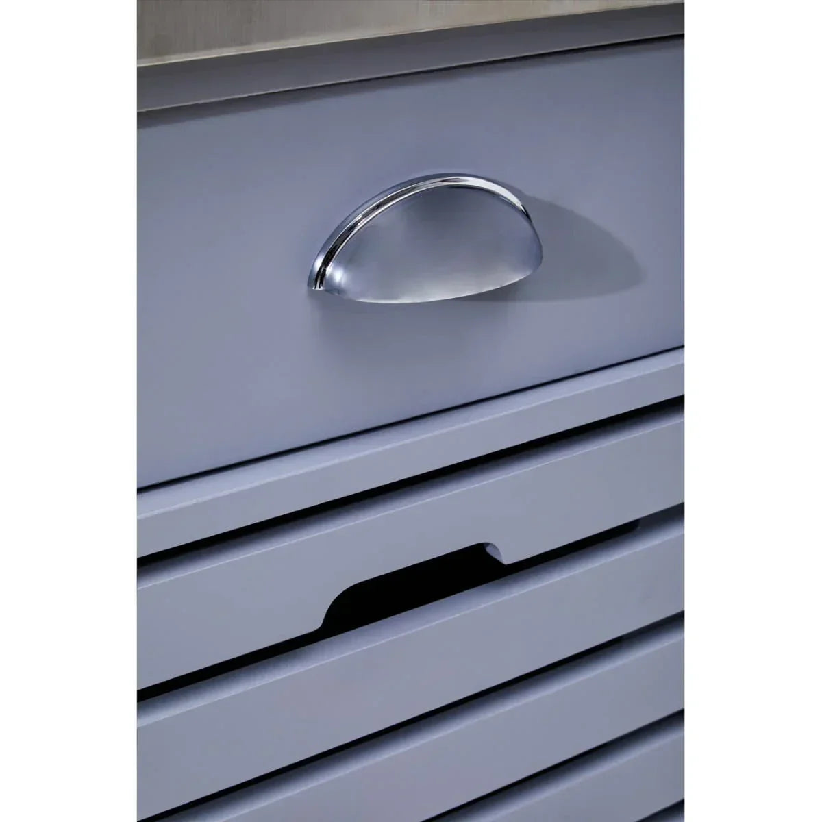 Close-up of grey chest of drawers with chrome cup handle and horizontal grooves