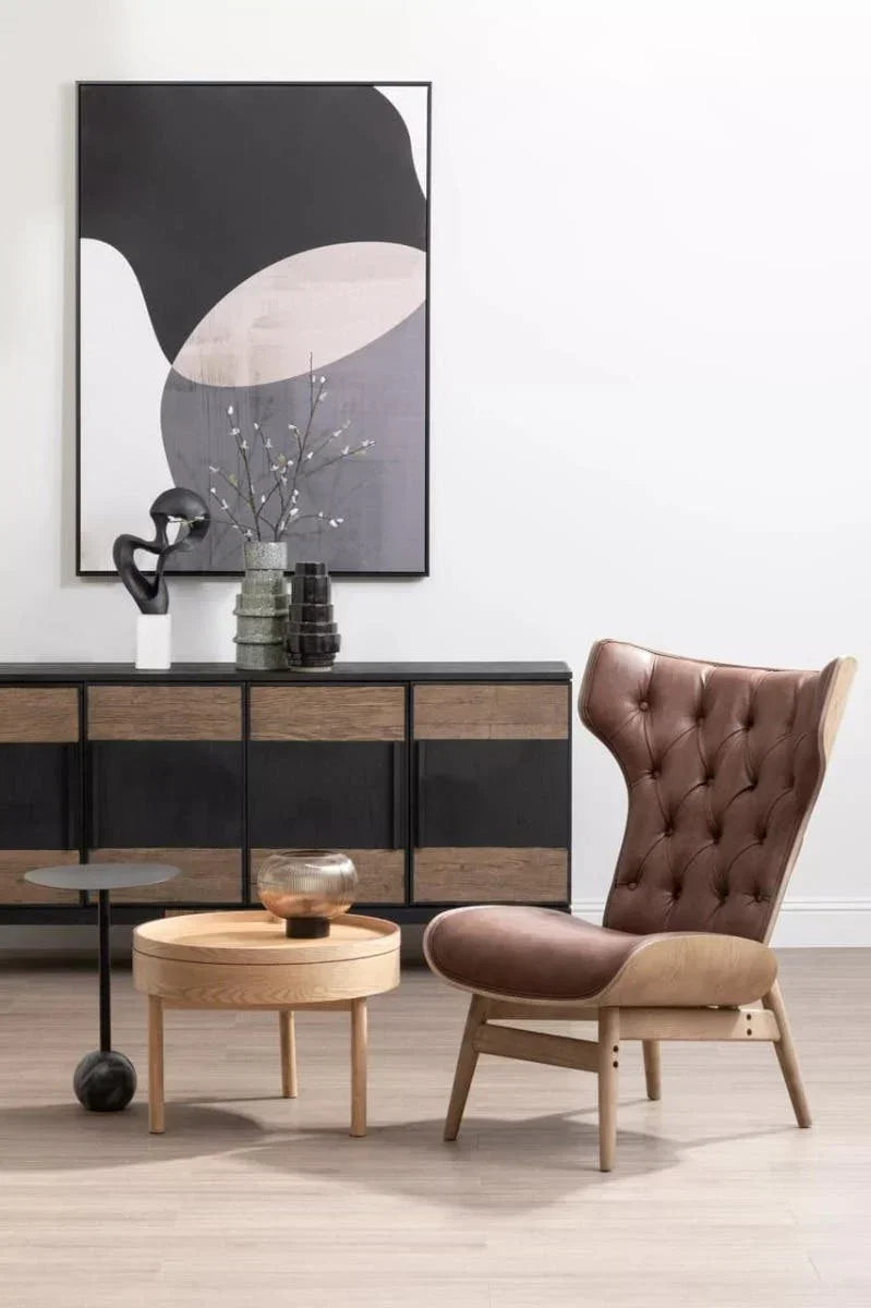 Brown leather accent chair with tufted back, round wooden coffee table, modern sideboard