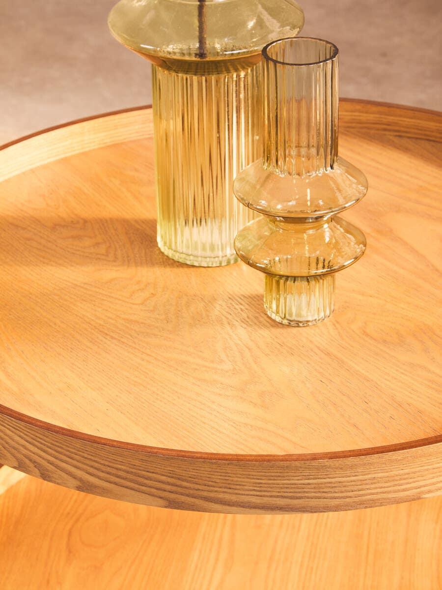 Round wooden table with fluted glass vases as tabletop decor
