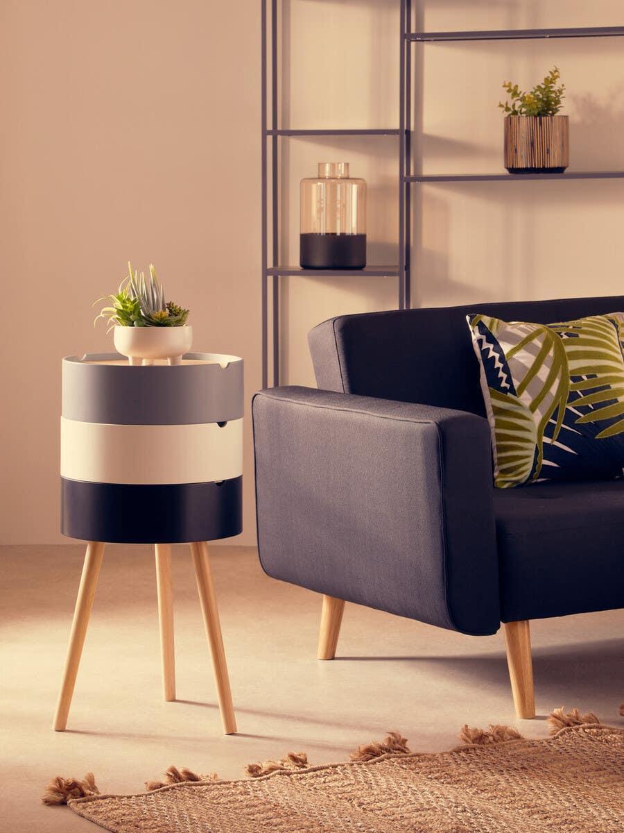 Modern side table with black and white drawers beside sofa, plant decor on top