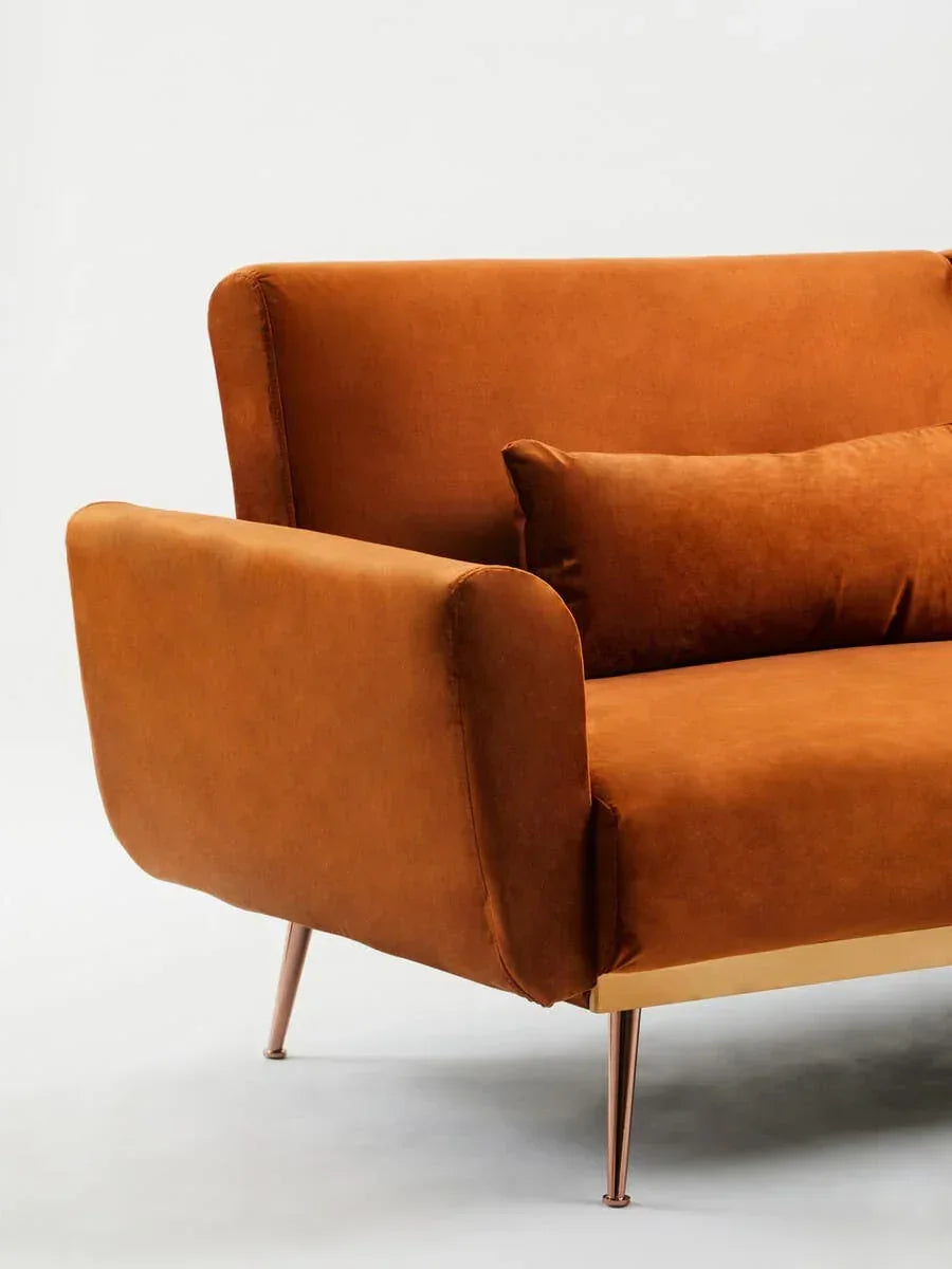 Burnt orange velvet sofa with matching cushion and gold metal legs, angled view