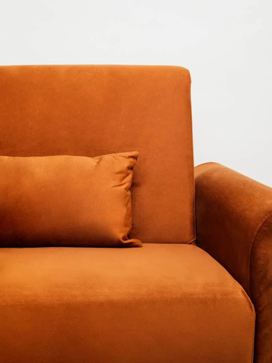 Burnt orange fabric sofa armrest and back with matching cushion, close-up view