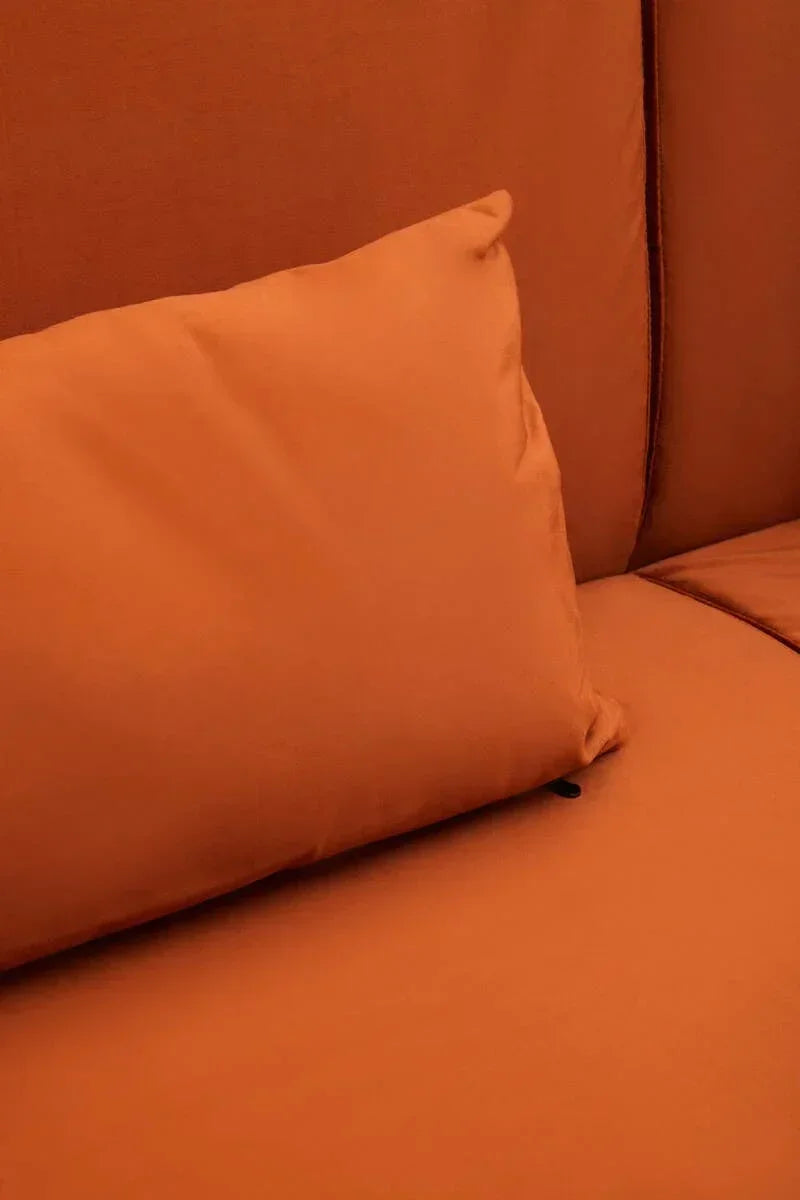 Close-up of orange sofa cushion on matching upholstered seat