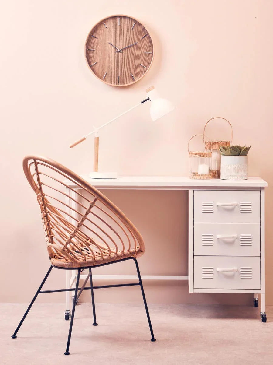 Rattan dining chair with black metal legs at white desk, wood wall clock above, modern decor