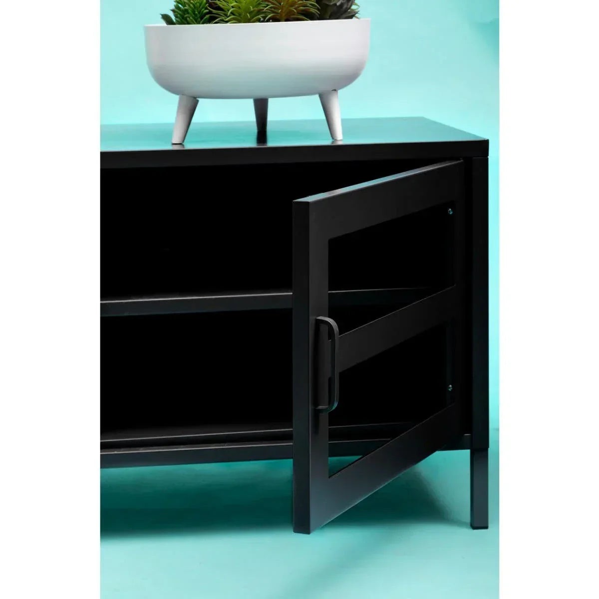 Black metal storage cabinet with glass door open and a white plant pot on top