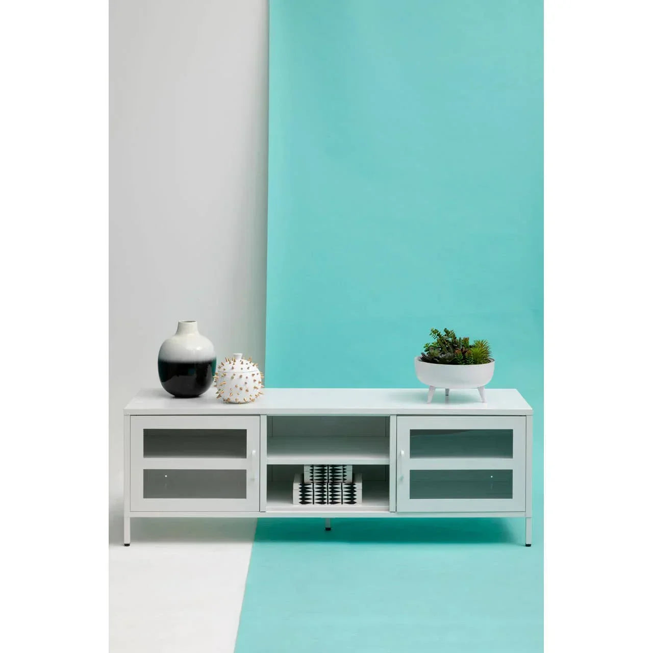 White TV unit with glass doors, decorative vases, and plant on minimalist background