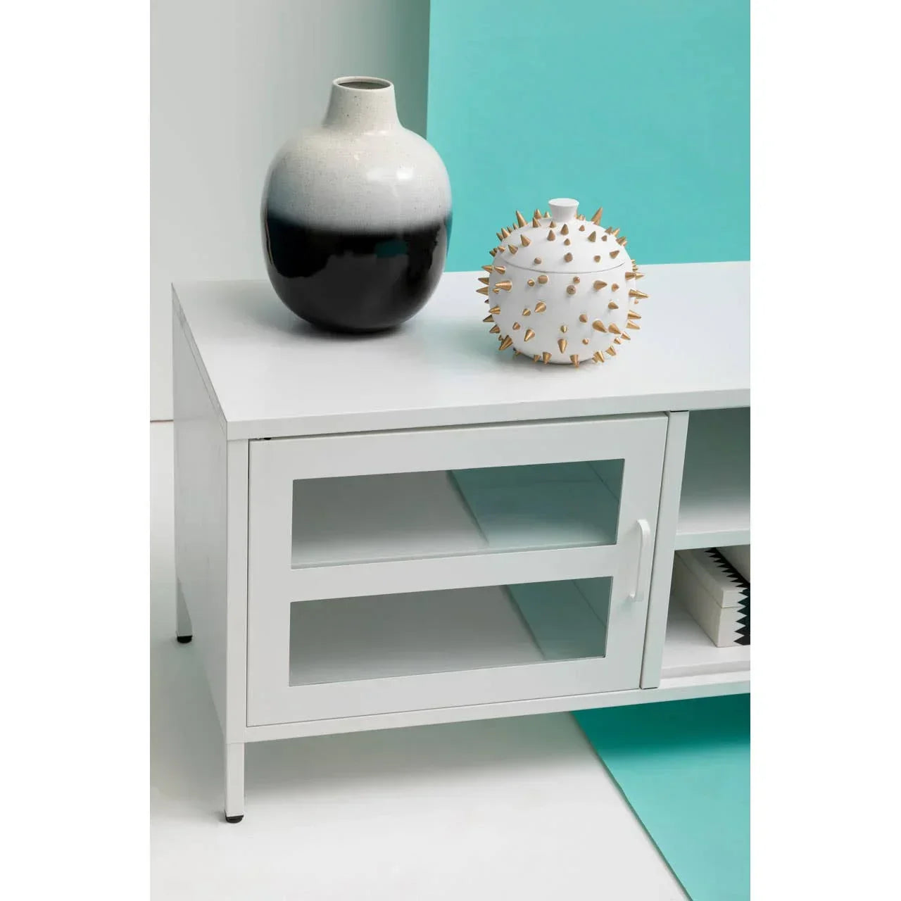 White TV unit with glass door, ceramic vases on top and books inside shelves
