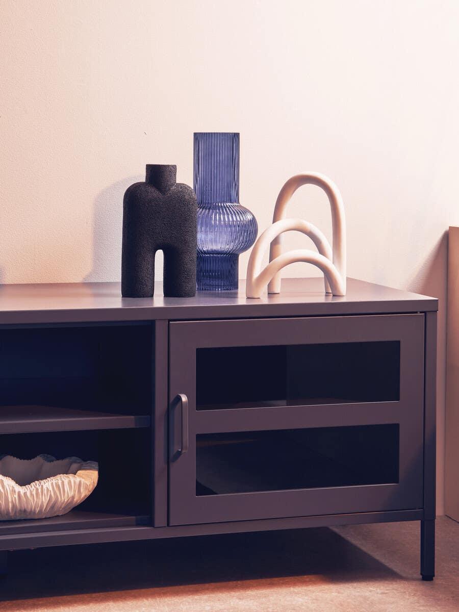 Modern dark TV unit with glass doors and decorative vases styled on top