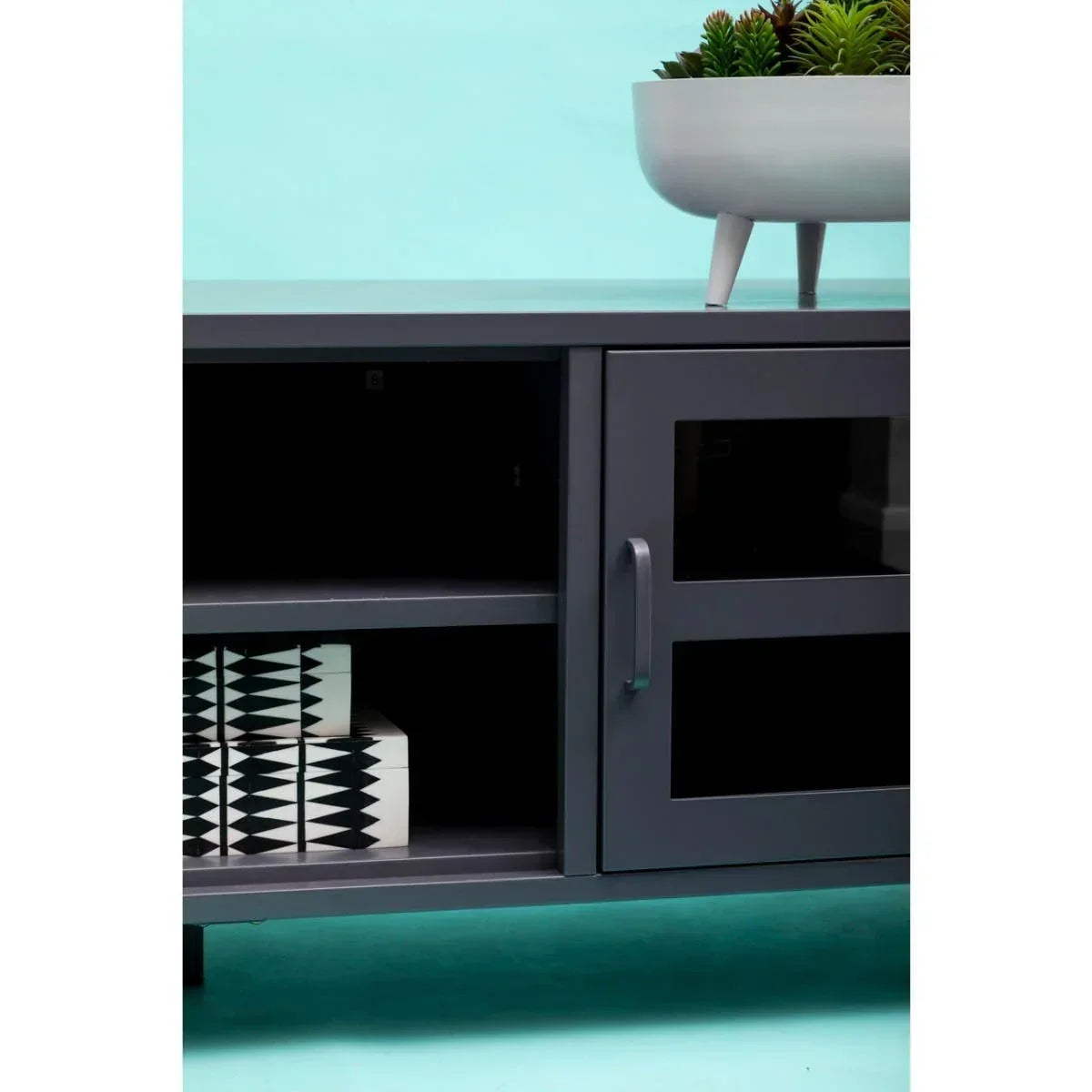 Grey media unit with black glass doors, open shelving, and books, blue background