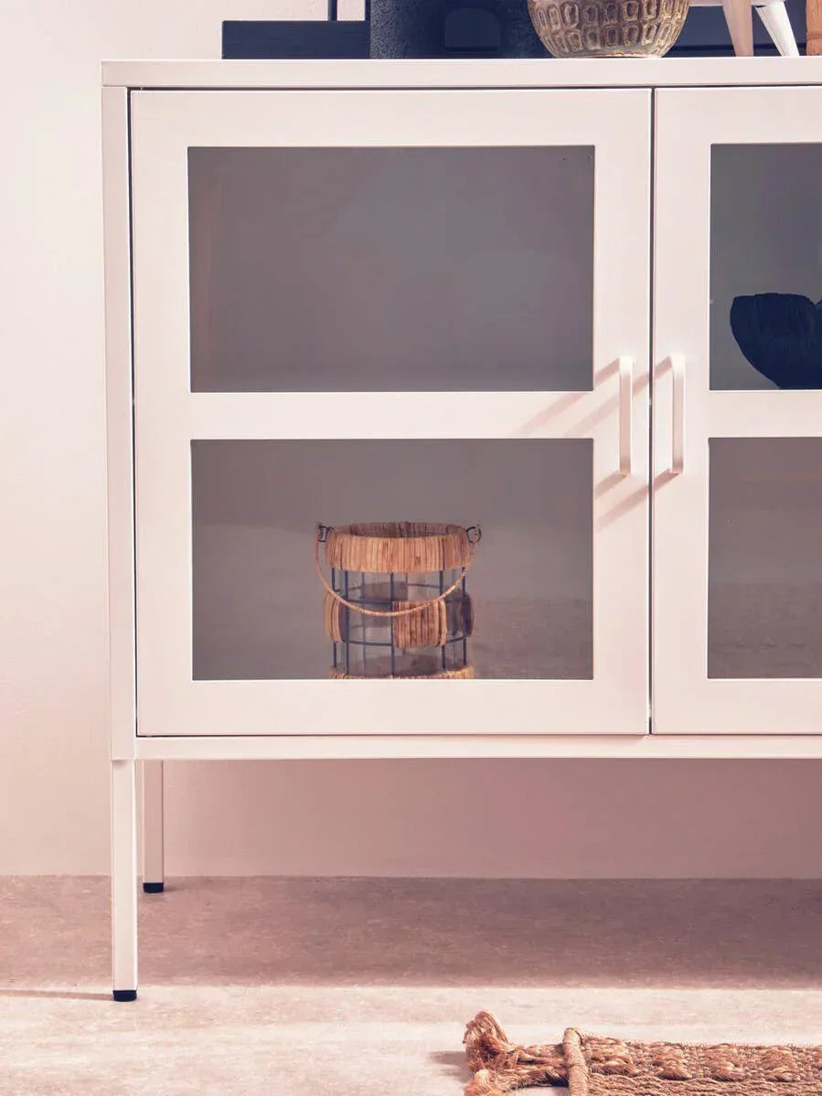 White glass display cabinet with metal legs and modern handles, shown in a living room setting