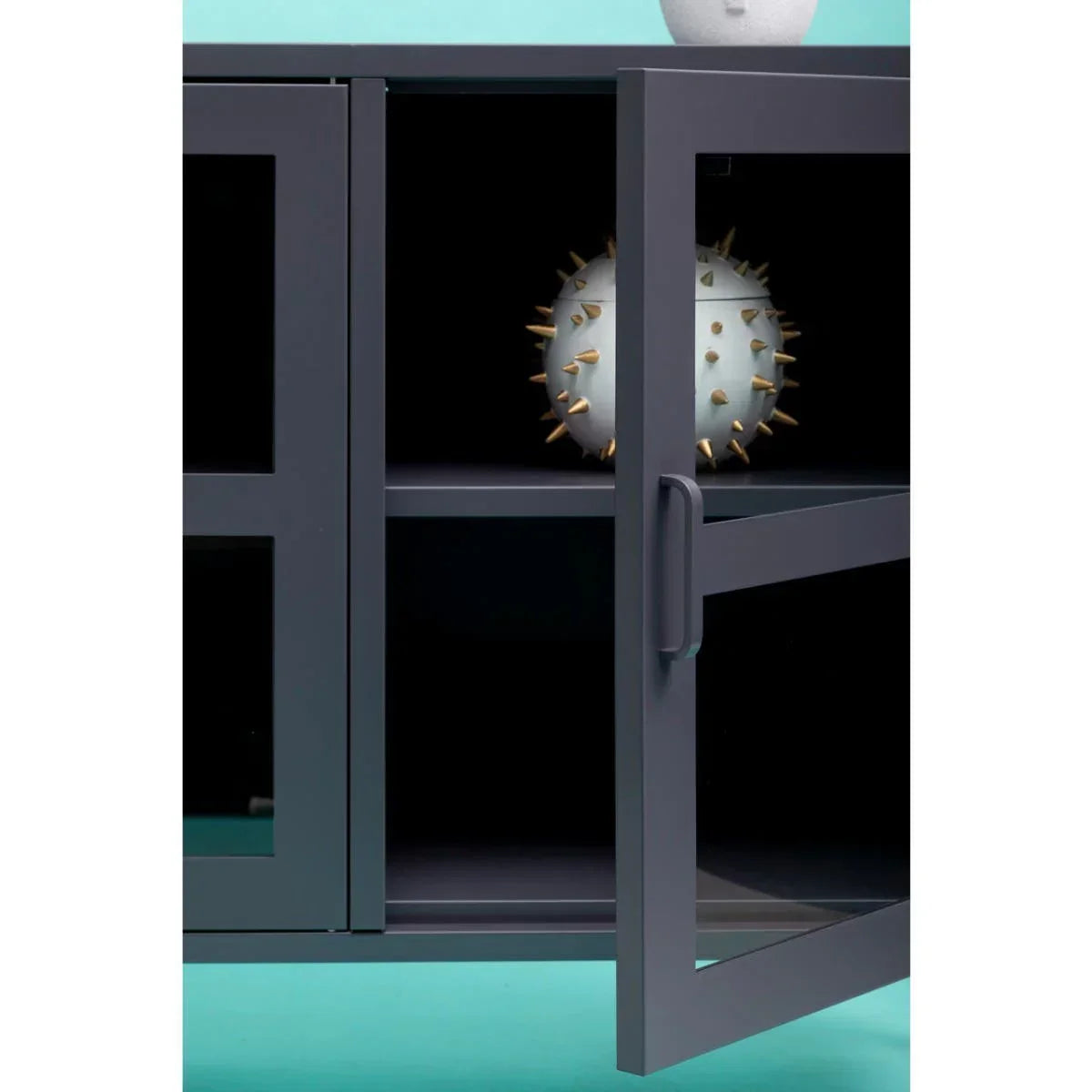 Black metal glass display cabinet with open door and shelf decor on turquoise background