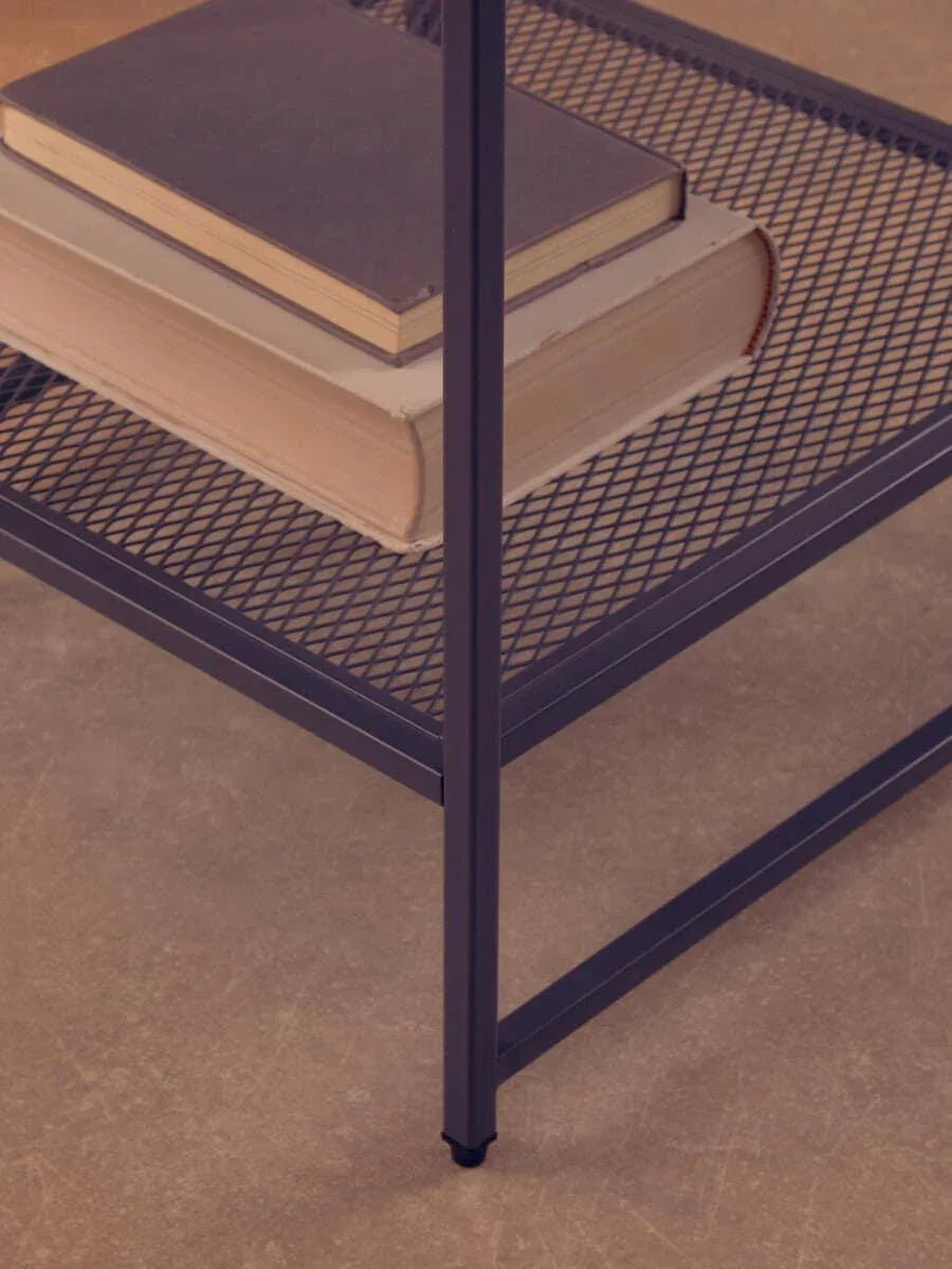 Black metal mesh shelf with stacked books on modern furniture unit