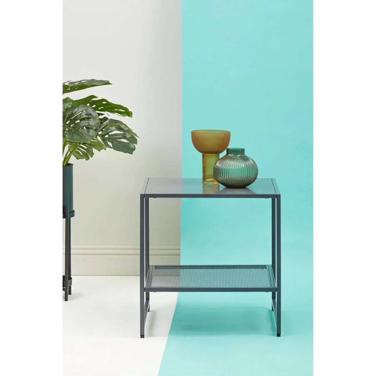 Metal side table with glass top, mesh shelf, amber vase and green ribbed vase