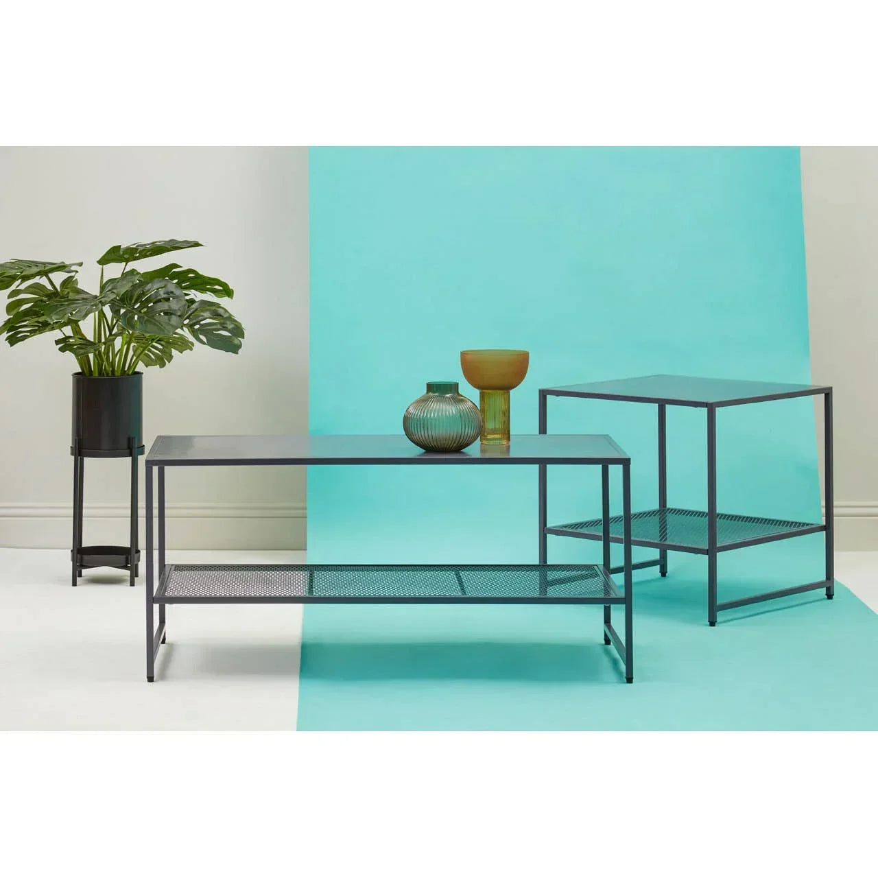 Black metal coffee table and side table set with mesh shelves against blue backdrop