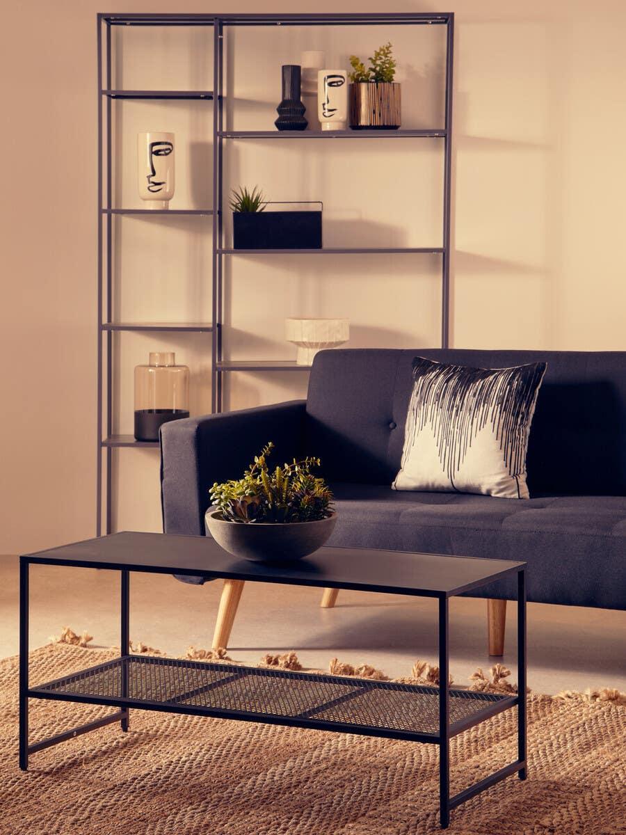 Black metal coffee table with mesh shelf in modern living room with dark sofa and shelving unit