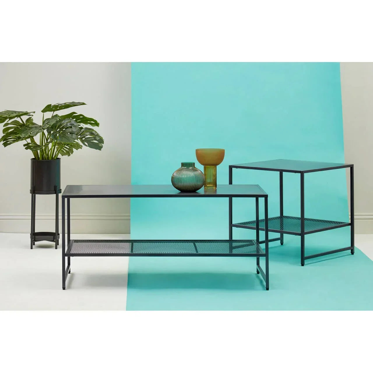 Black metal coffee table and side table with mesh shelves, decorative vases, and plant