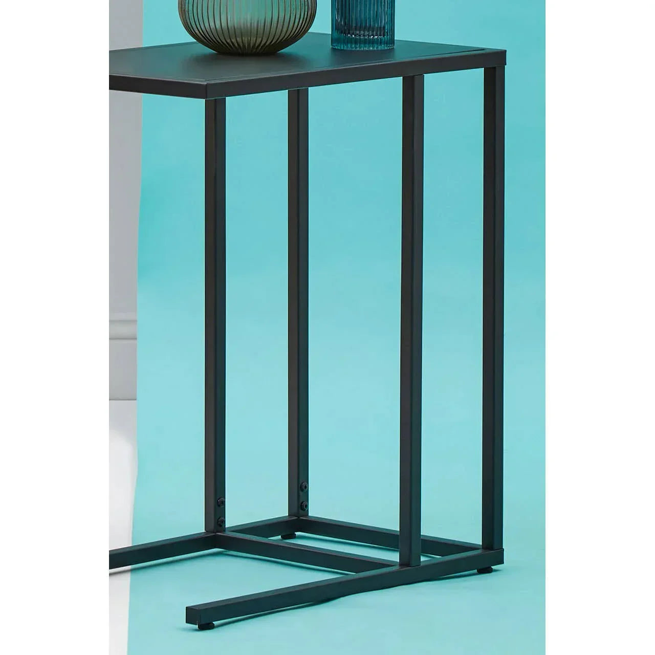 Black metal side table with rectangular top and vase on blue background