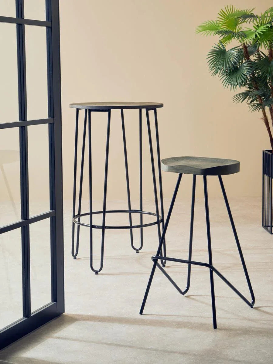 Set of two black metal bar stools with round seats in modern interior beside window