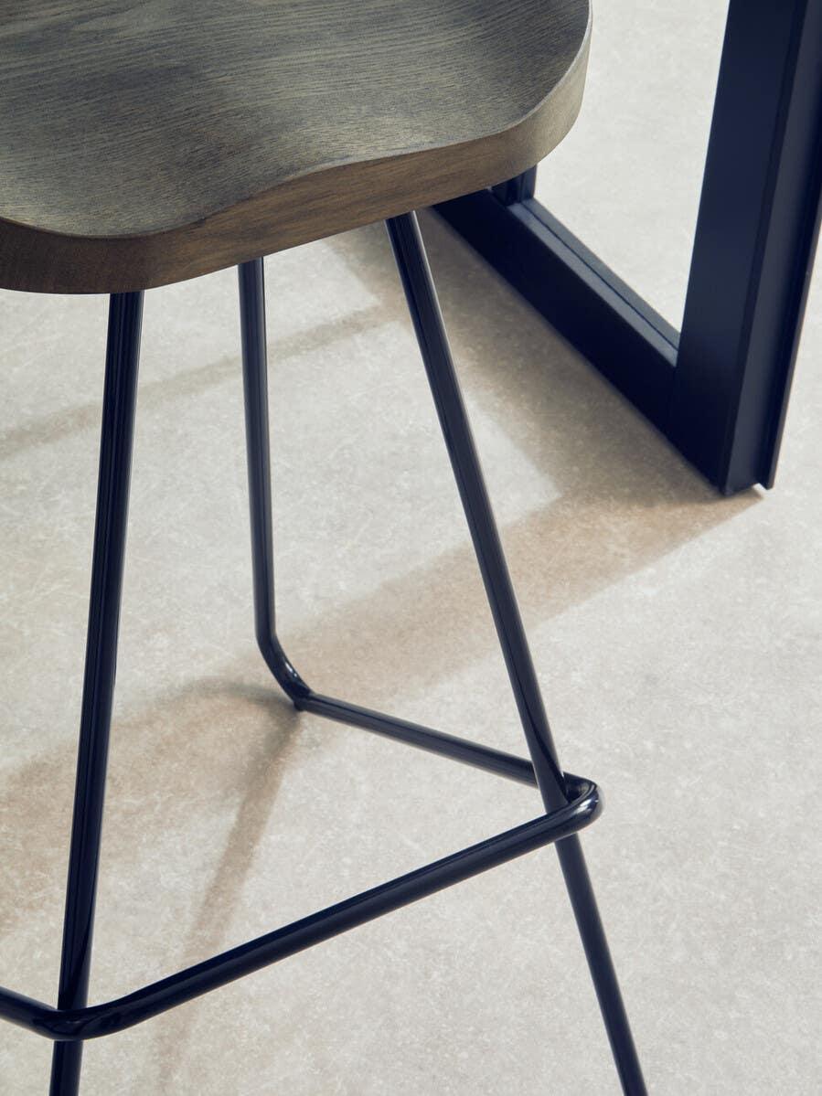 Wood bar stool with black metal legs on light tiled floor