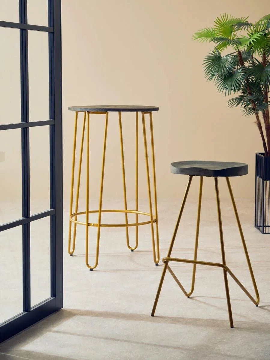 Set of modern side tables with black tops and gold metal legs beside a potted plant
