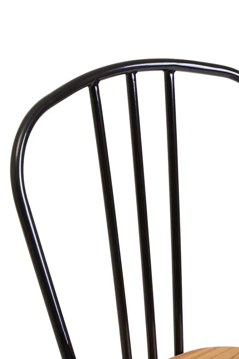 Black metal dining chair backrest with vertical slats and wooden seat corner