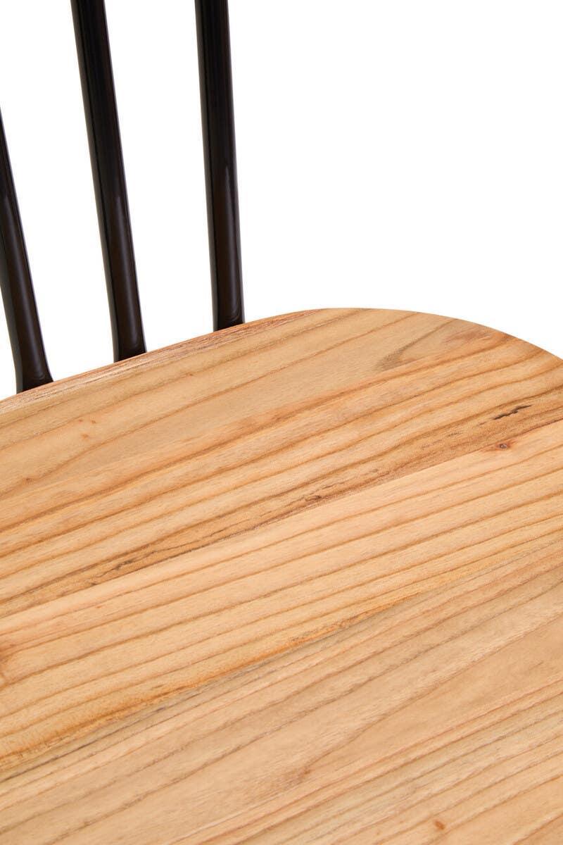 Close-up of wooden dining chair seat with black metal spindle backrest