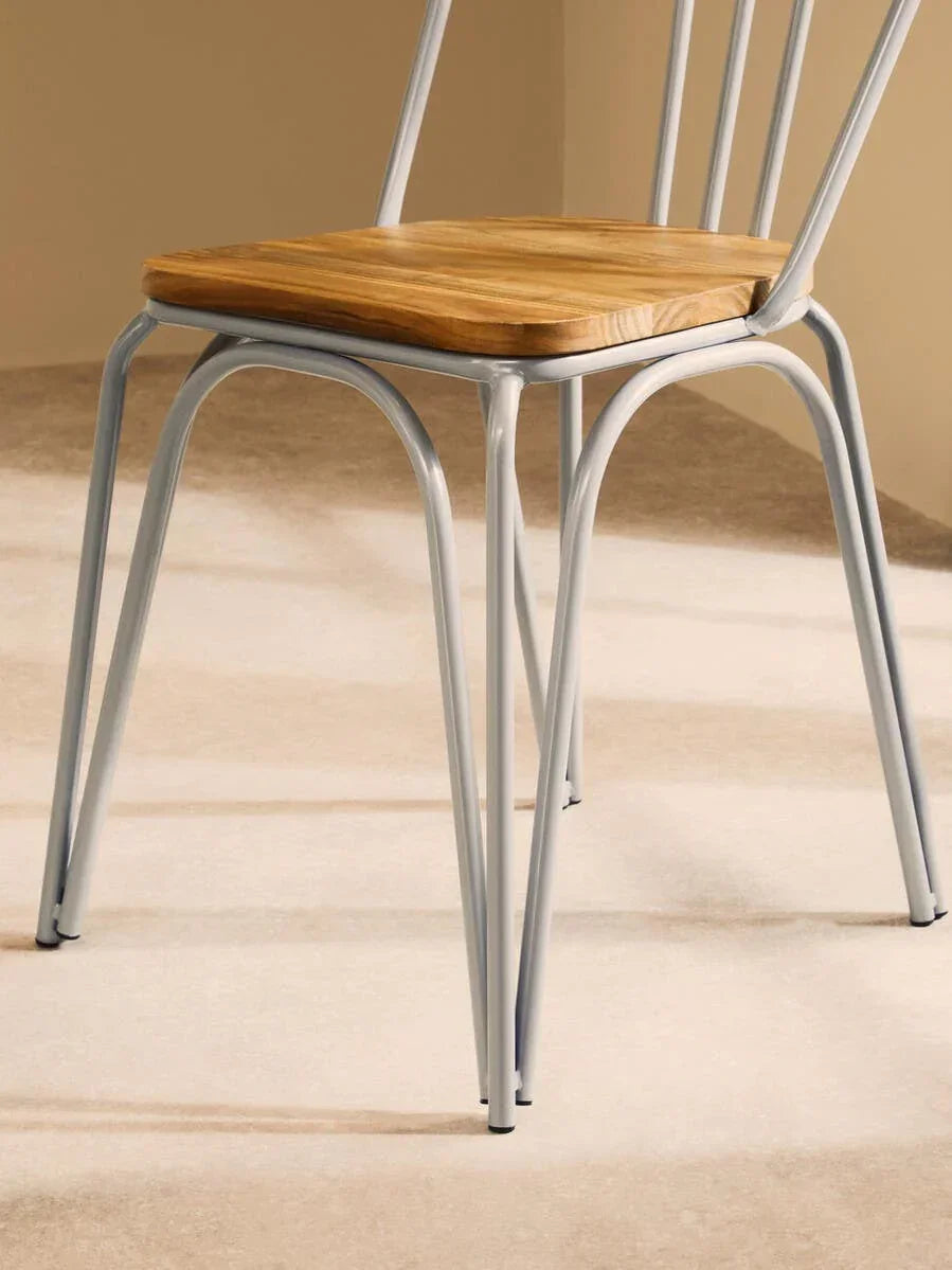 Metal frame dining chair with light wood seat on carpeted floor