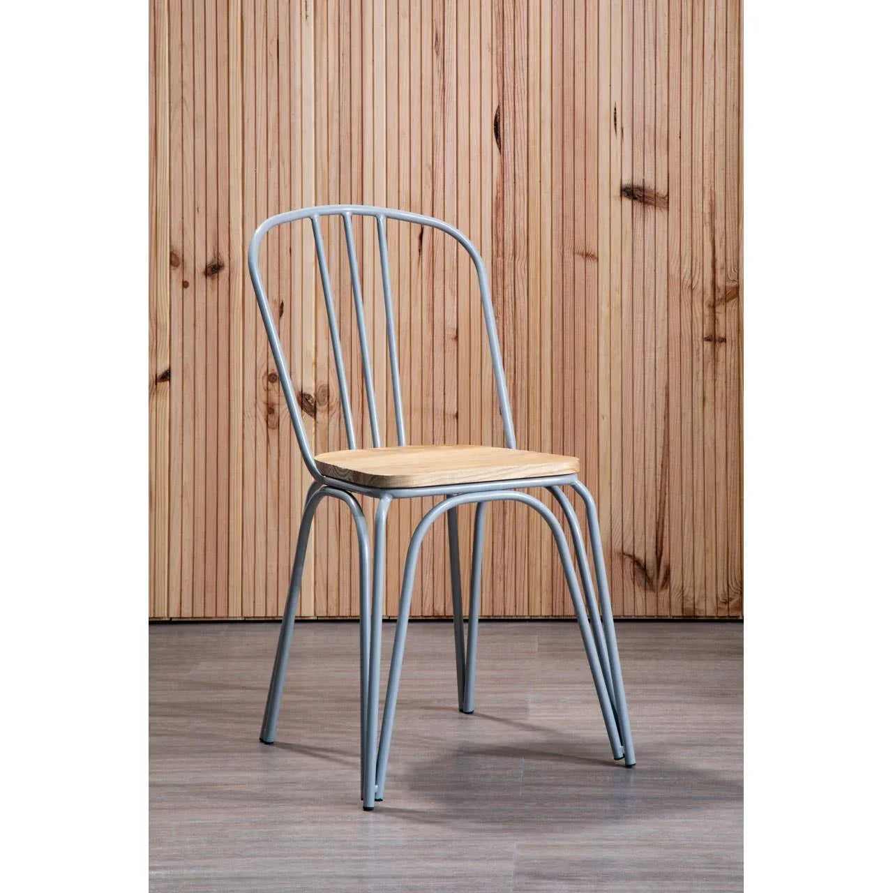 Metal dining chair with light wood seat against wooden panel wall on laminate floor