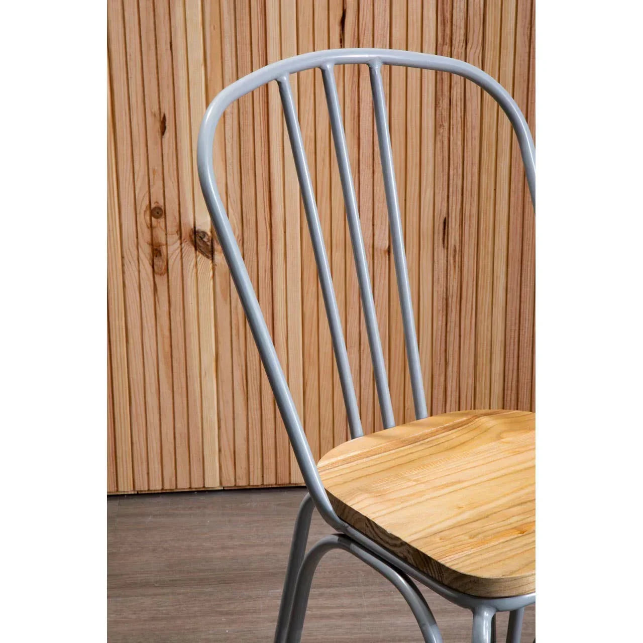 Metal dining chair with light wood seat and vertical slat backrest against wood panel wall