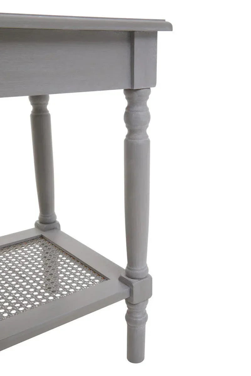 Closeup of grey wooden table with turned legs and rattan shelf