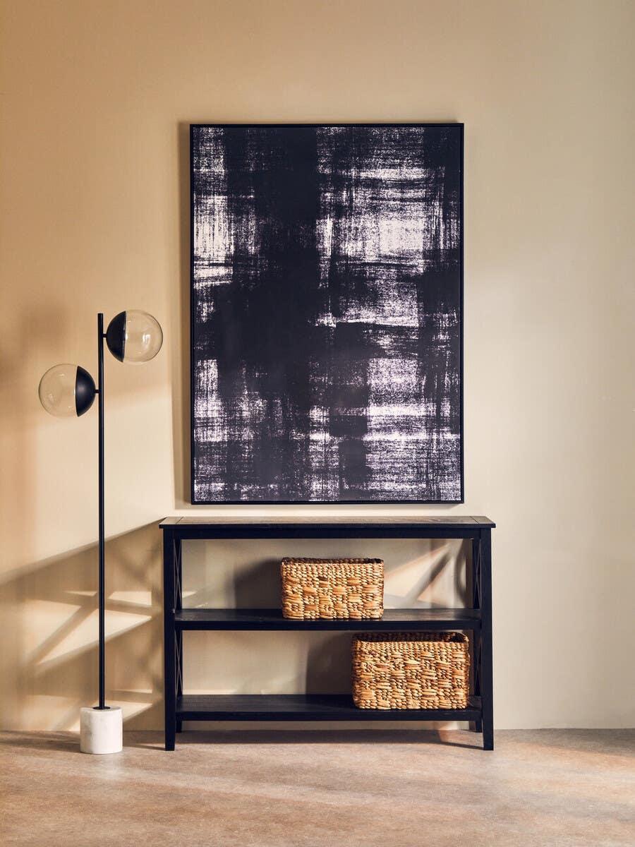 Black console table with woven storage baskets and abstract wall art against beige wall