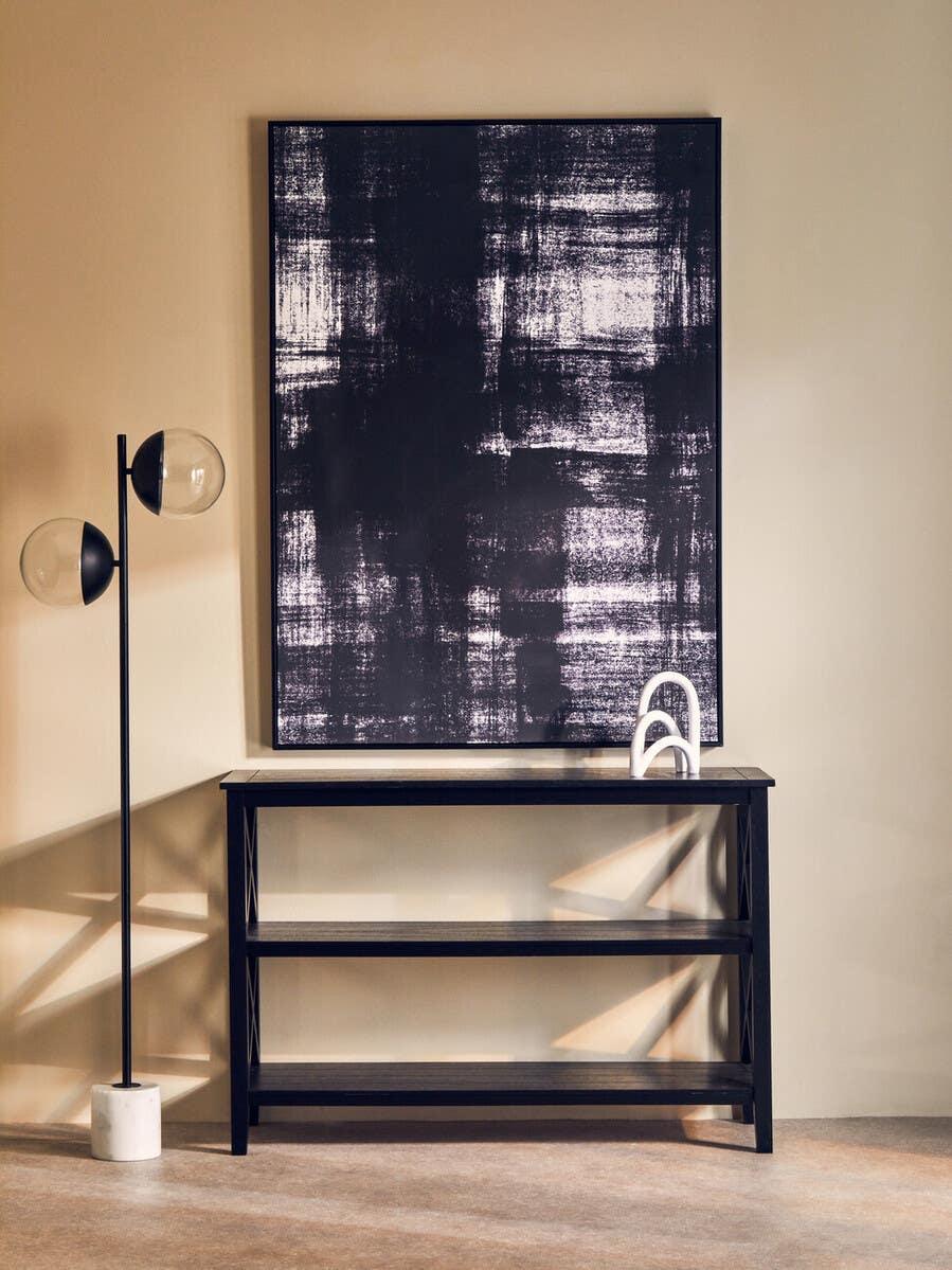 Black console table with marble effect top, modern floor lamp, abstract wall art