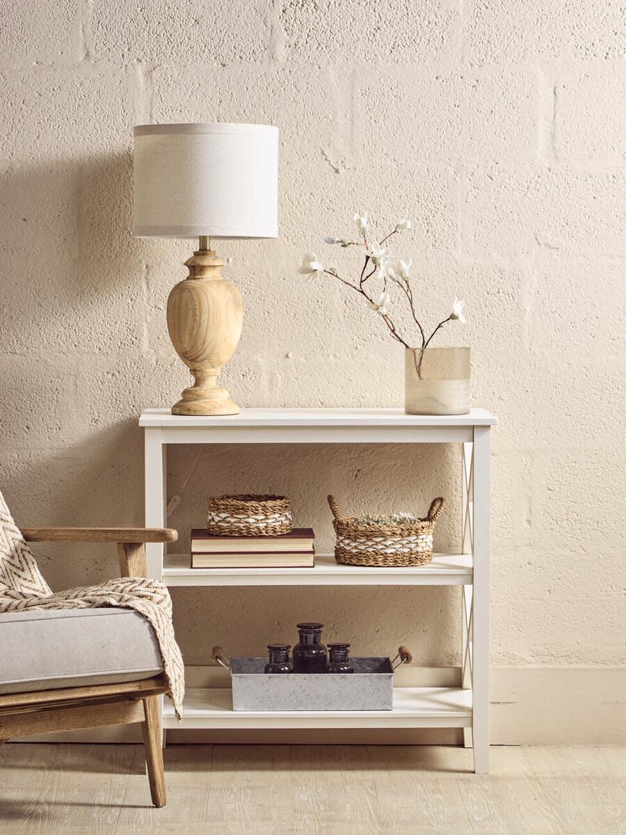 White wooden console table with lamp, books, baskets and vase in living room setting