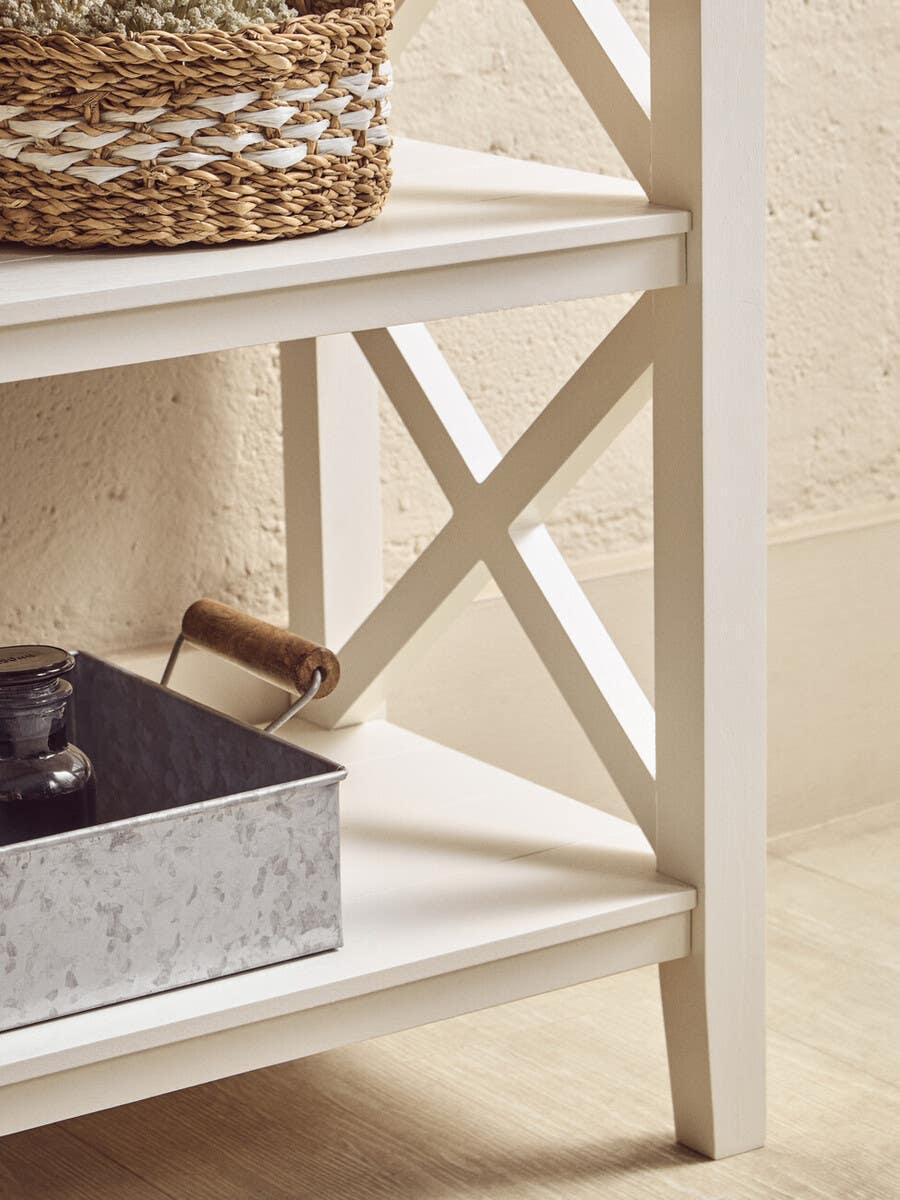 White wooden shelving unit with cross-frame detail and storage basket on lower shelves