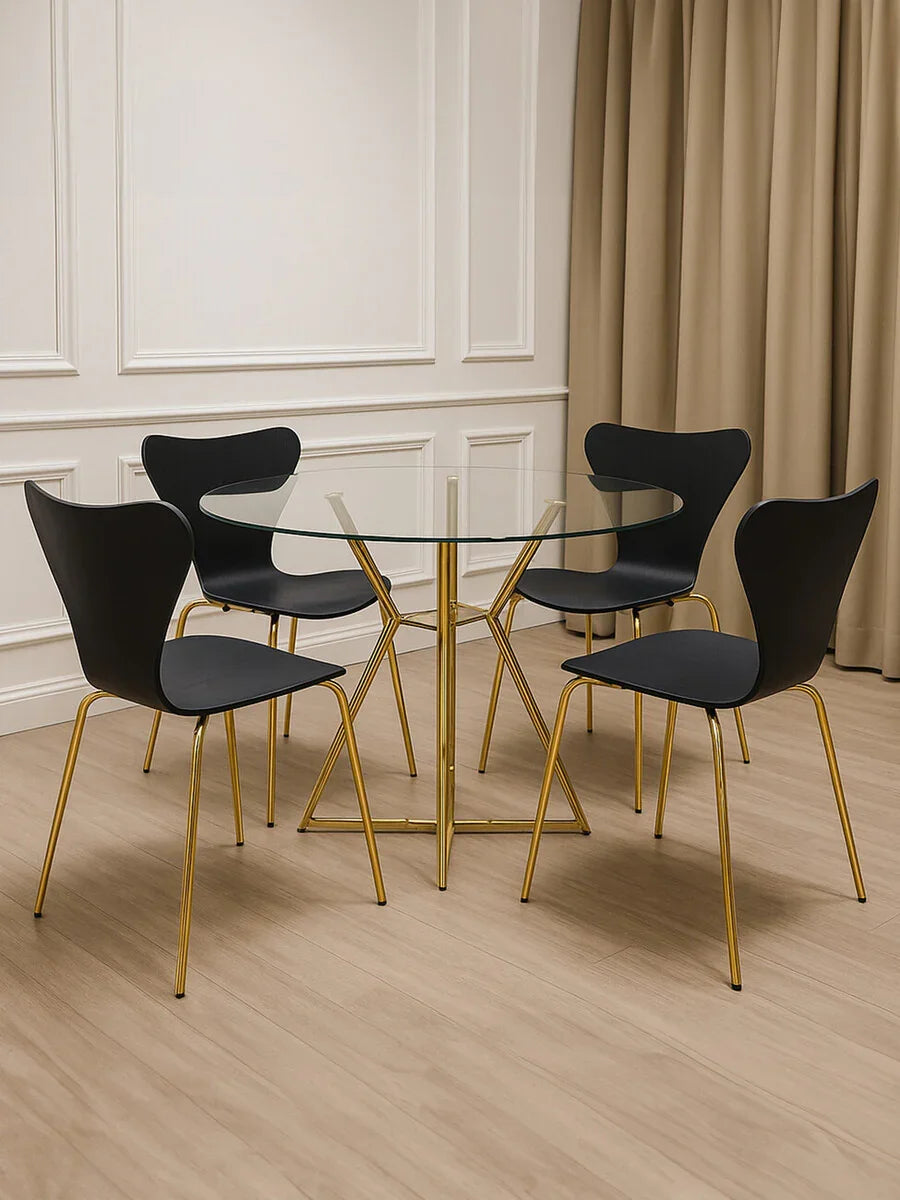 Glass dining table with gold metal legs and four black chairs in modern dining room