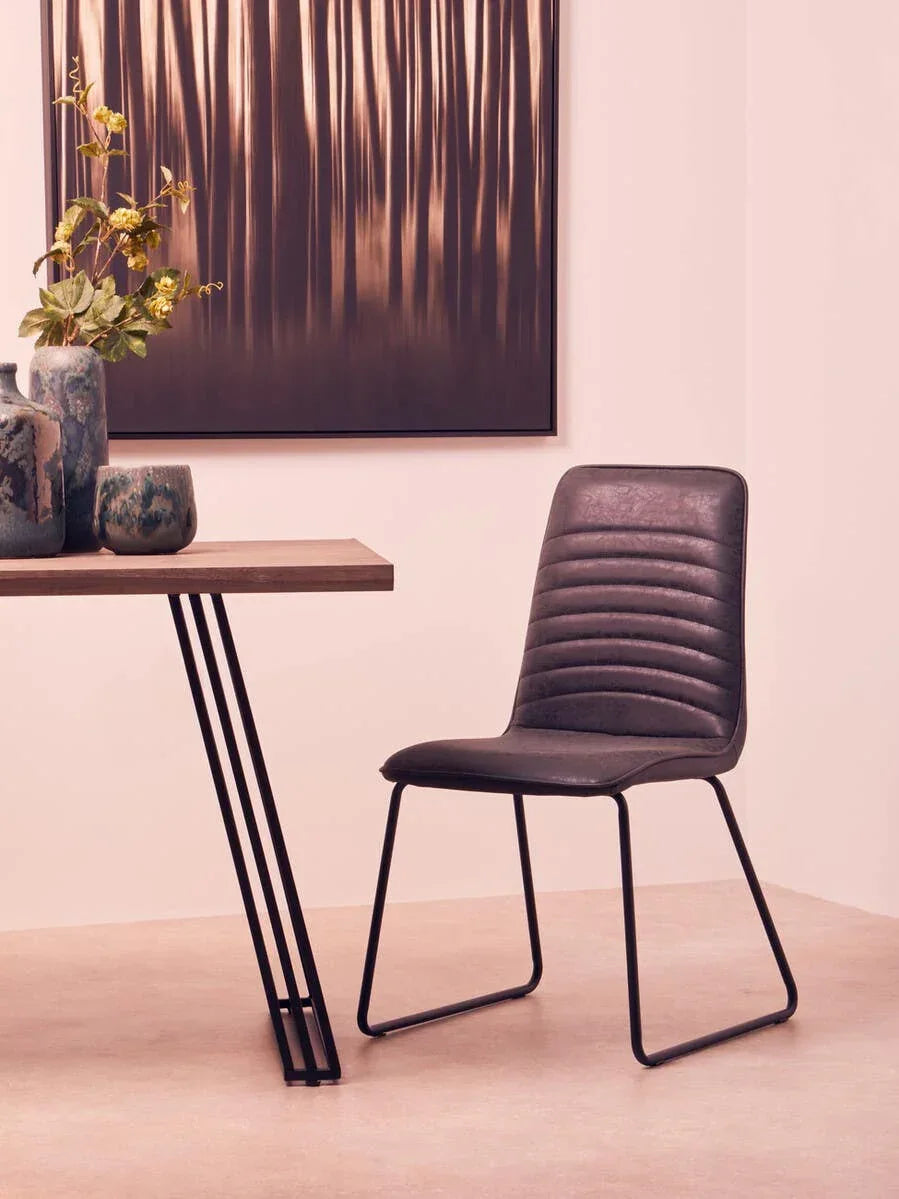 Grey faux leather dining chair with black metal legs beside modern wooden table
